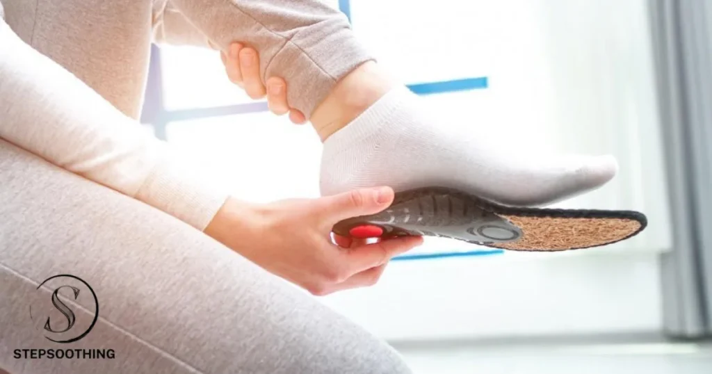 A person is sitting down and trying on a size of insole. They are wearing white socks and grey trousers.